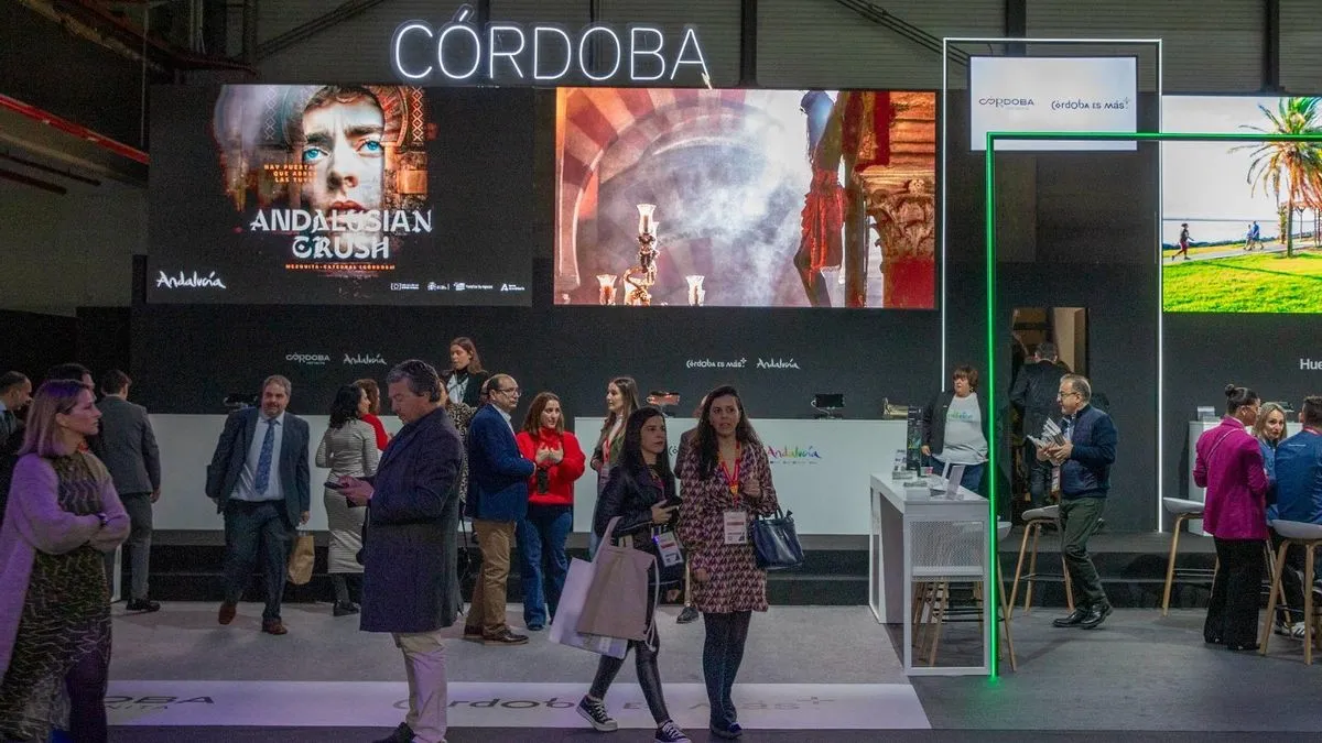 Pantallas de gran formato en el pabellón de Andalucía en FITUR 2024, con visitantes y personal del stand.